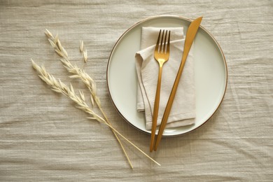 Photo of Stylish setting with cutlery, napkin and plate on light table, top view