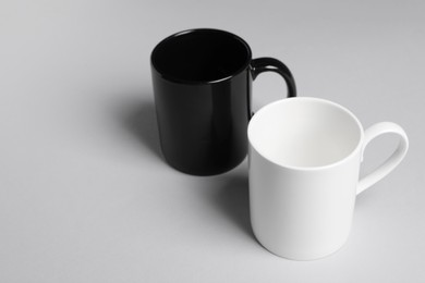 Photo of Black and white ceramic mugs on light background. Space for text