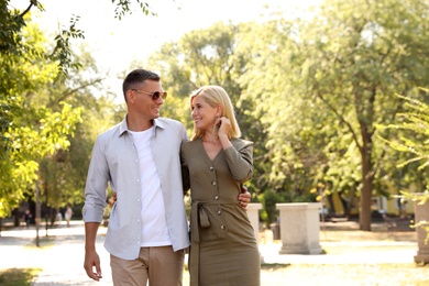 Happy couple walking along park on summer day