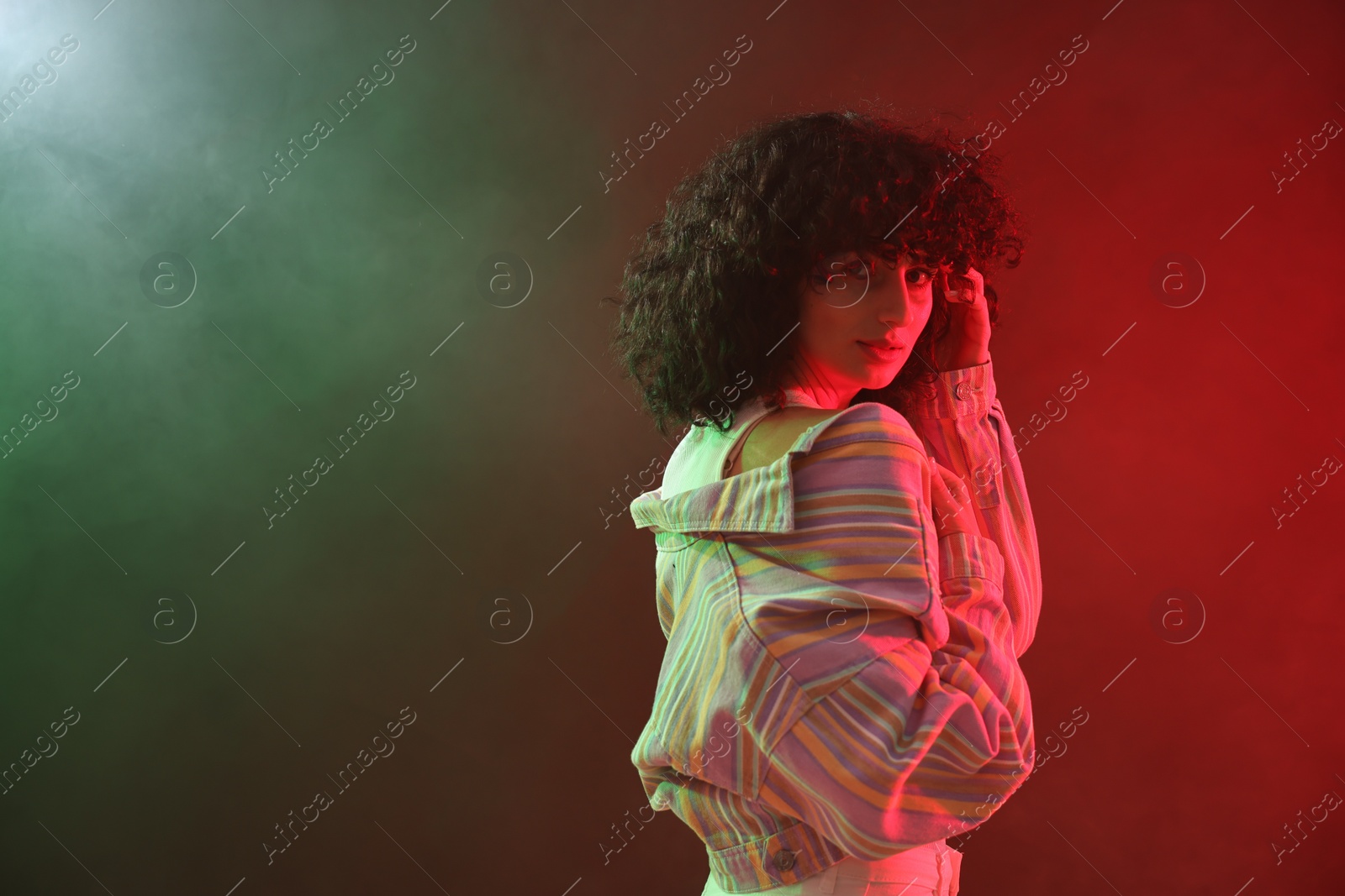 Photo of Beautiful young woman posing on color background in neon lights. Space for text