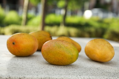 Photo of Delicious ripe juicy mangos on table outdoors