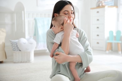 Young woman with her cute baby at home, space for text