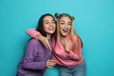 Two beautiful women laughing together against color background