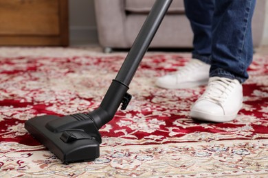 Man cleaning carpet with vacuum cleaner at home, closeup