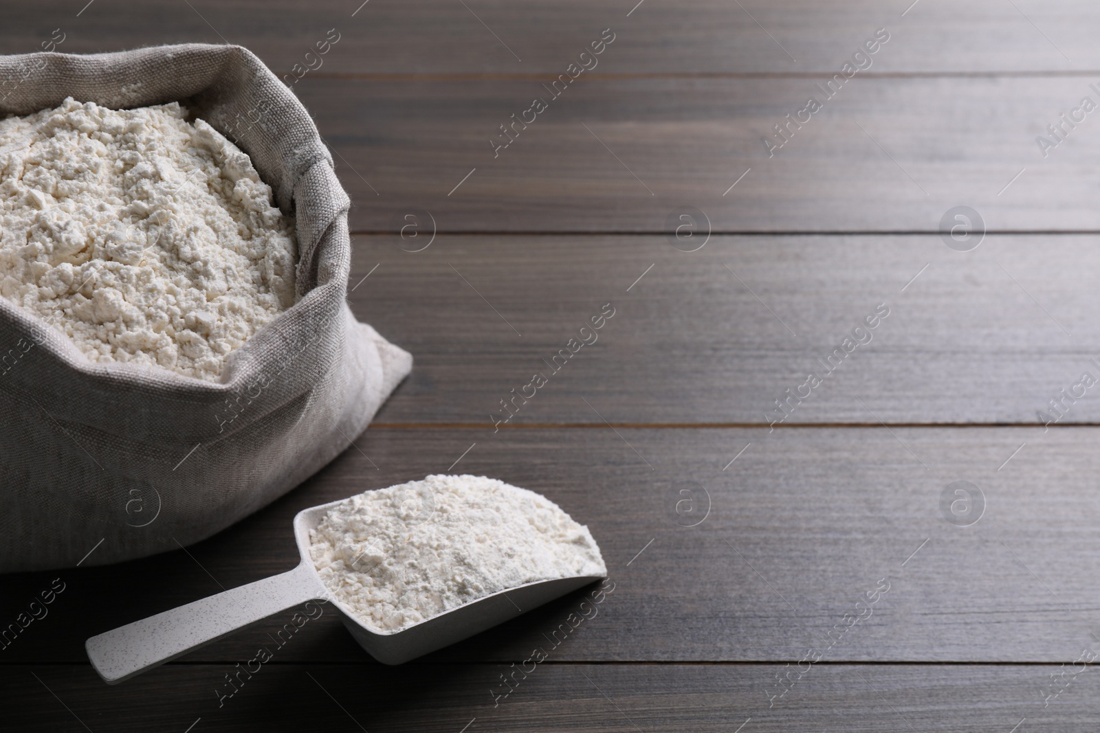 Photo of Sack with flour on wooden background. Space for text