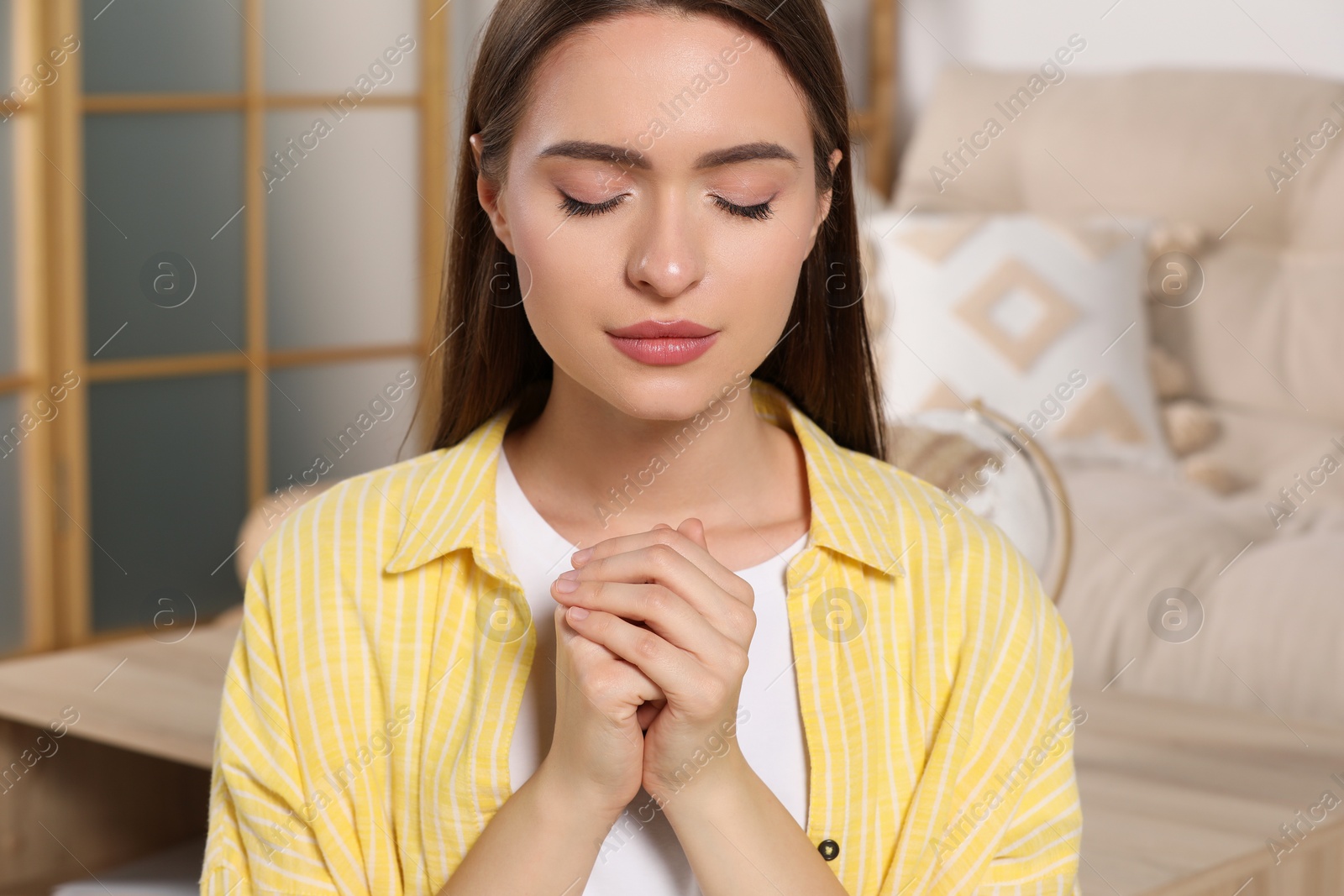 Photo of Woman with clasped hands praying at home