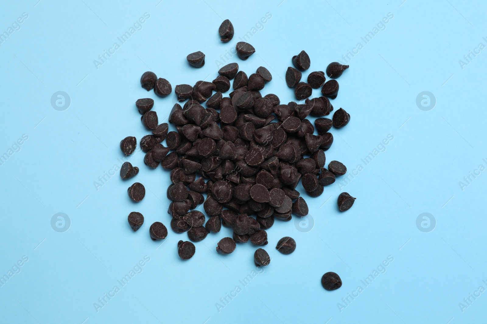 Photo of Pile of delicious chocolate chips on light blue background, top view