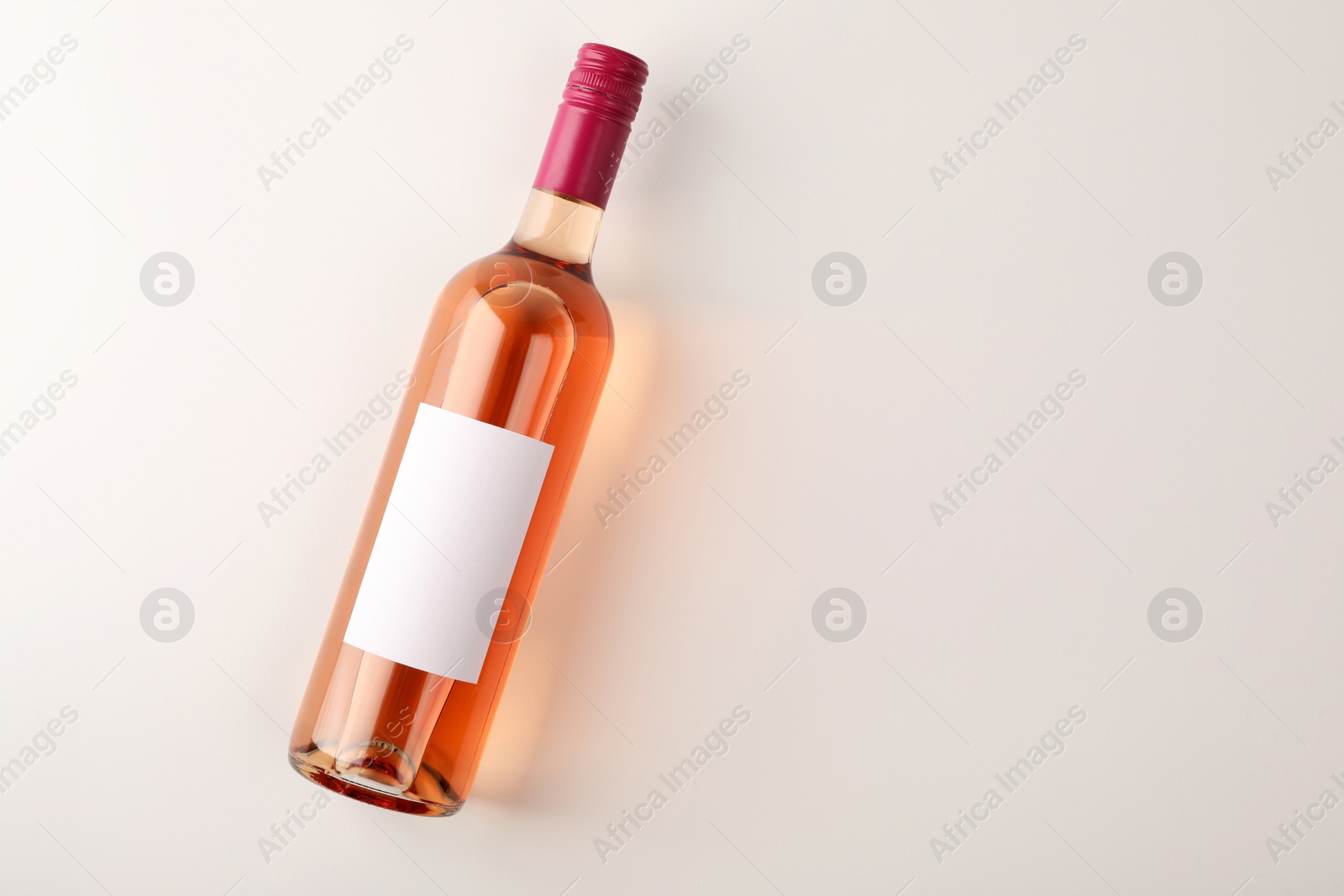 Photo of Bottle of tasty rose wine on white background, top view. Space for text