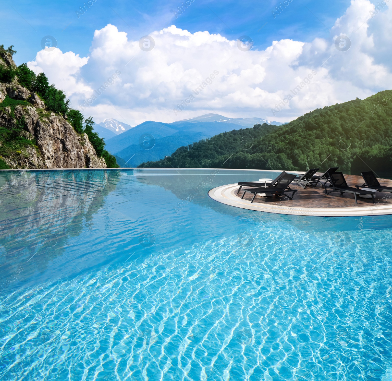 Image of Chaise longues near outdoor swimming pool at luxury resort and beautiful view of mountains on sunny day