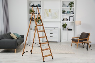 Photo of Wooden folding ladder on soft carpet in stylish room