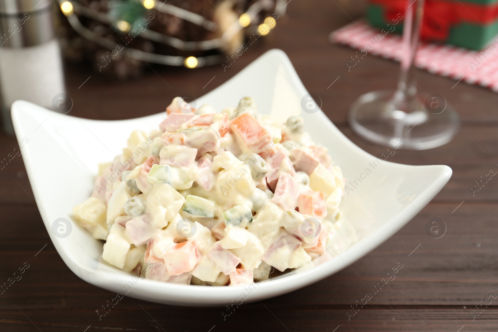 Photo of Traditional russian salad Olivier served on wooden table, closeup