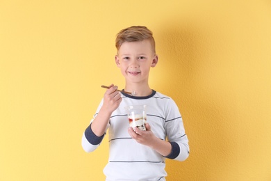 Little boy with yogurt on color background