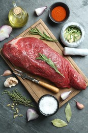 Photo of Piece of raw beef meat and spices on grey table, flat lay