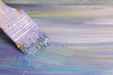 Photo of Strokes of colorful paints and brush on canvas, closeup