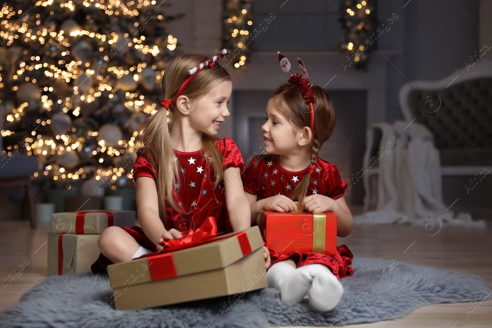 Photo of Cute little children with Christmas gifts in living room