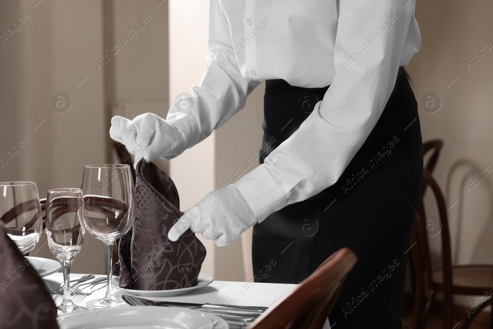 Photo of Woman setting table in restaurant, closeup. Professional butler courses