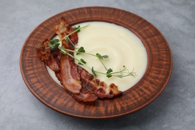 Photo of Delicious potato soup with bacon and microgreens in bowl on gray table, closeup