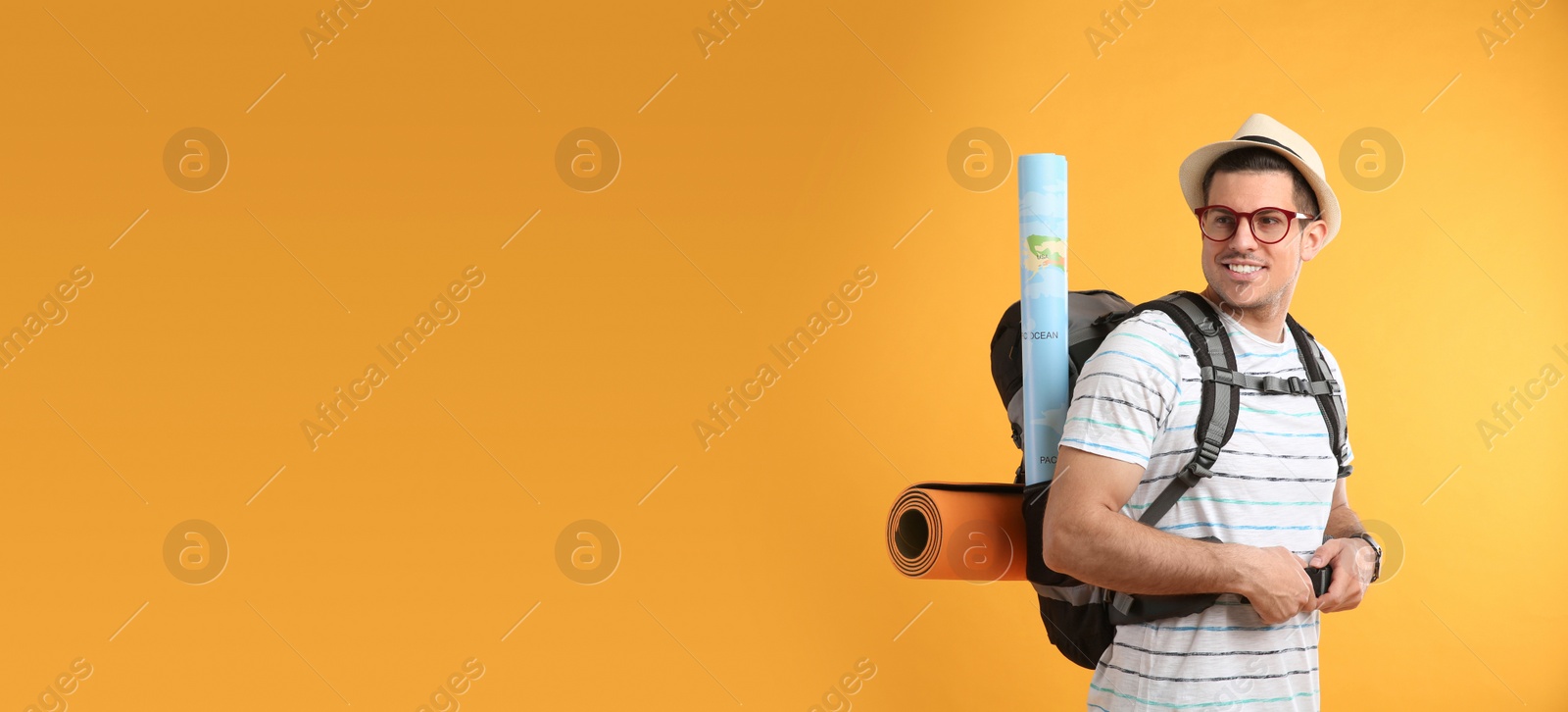 Photo of Male tourist with travel backpack on yellow background, space for text