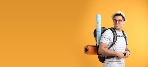 Photo of Male tourist with travel backpack on yellow background, space for text