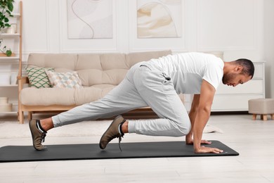 Photo of Man doing morning exercise on fitness mat at home