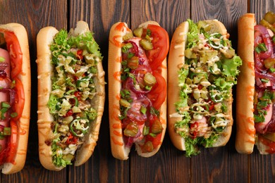 Different tasty hot dogs on wooden table, flat lay