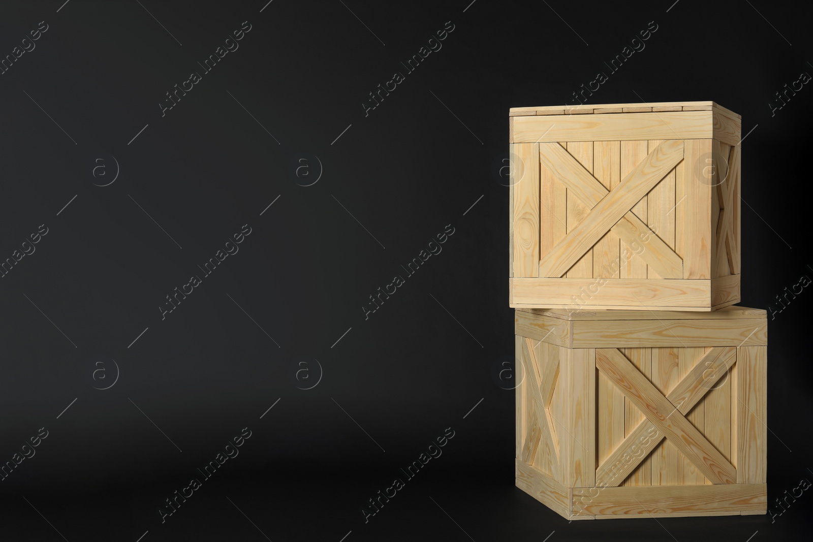 Photo of Wooden crates on black background, space for text. Shipping containers