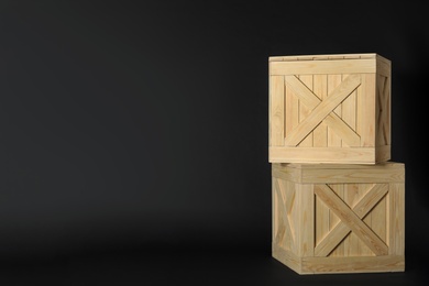 Wooden crates on black background, space for text. Shipping containers