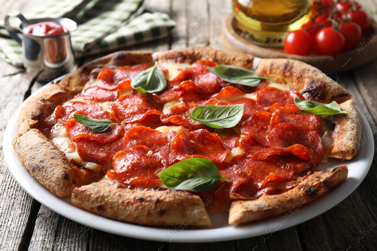 Photo of Tasty pepperoni pizza with basil, tomatoes and sauce on wooden table