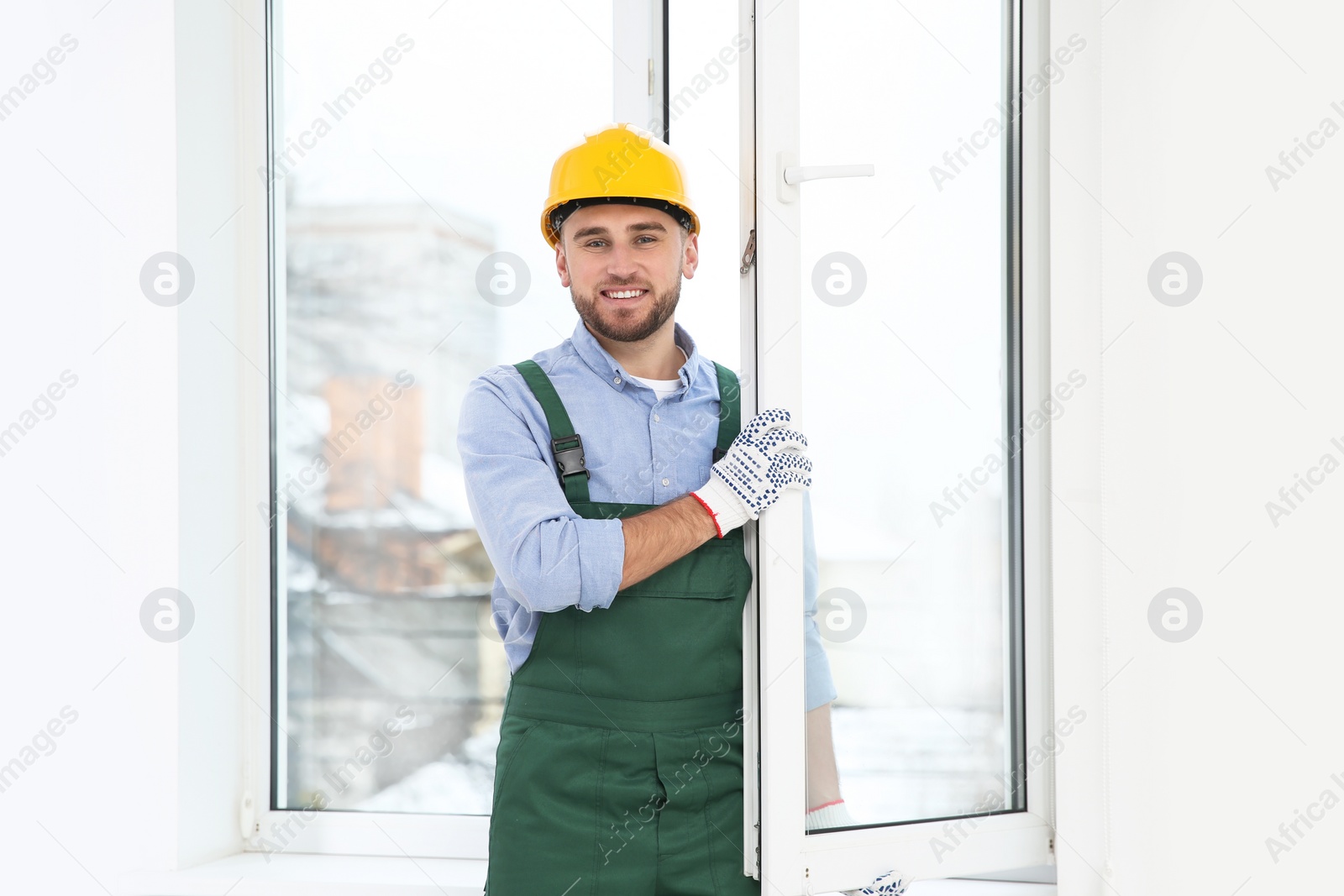 Photo of Construction worker installing plastic window in house