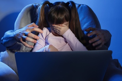 Photo of Stranger reaching frightened little child with laptop on color background. Cyber danger