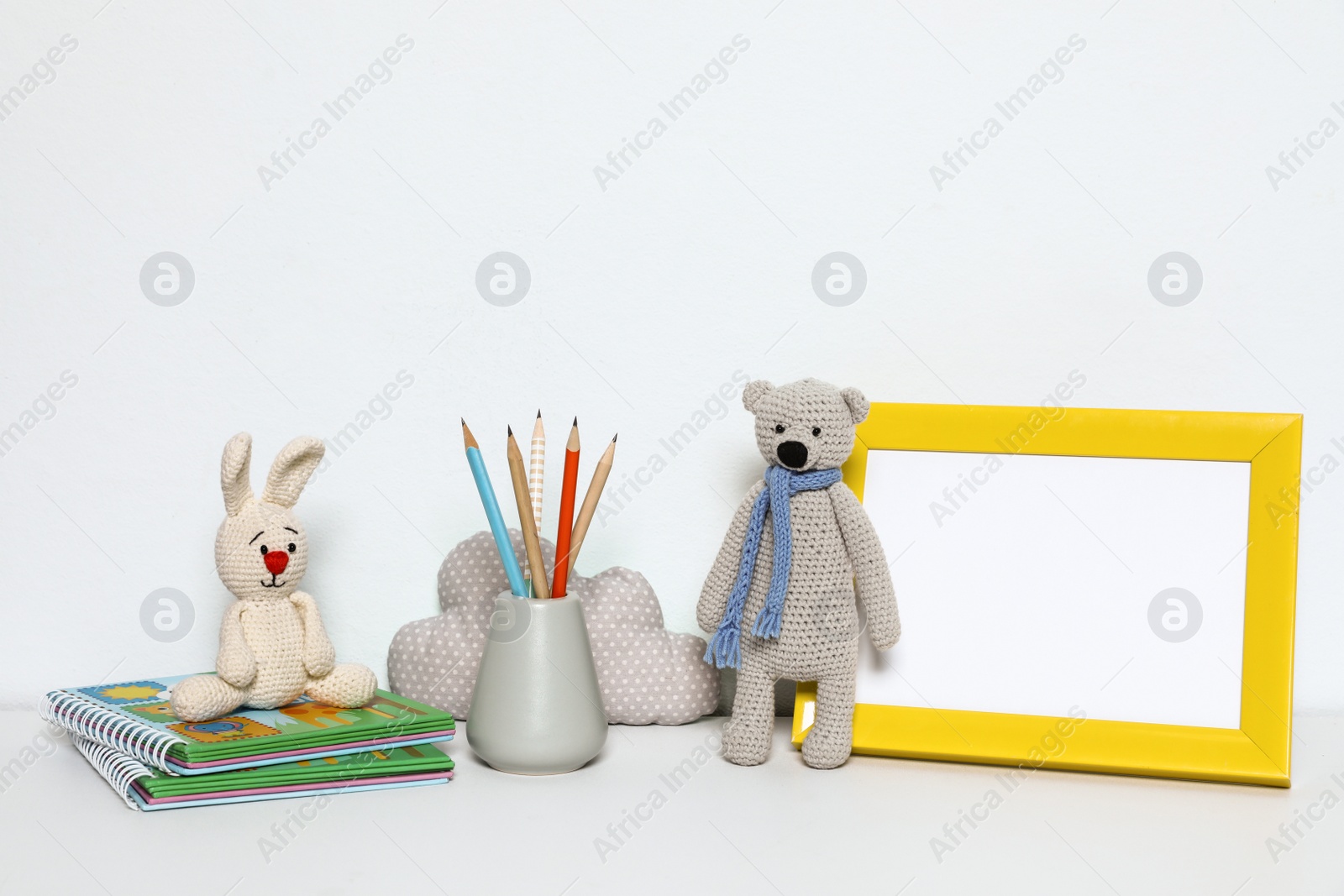 Photo of Composition with soft toys and photo frame on white background. Child room interior decor