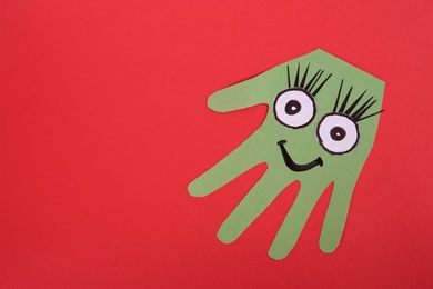 Photo of Funny green hand shaped monster on red background, top view with space for text. Halloween decoration