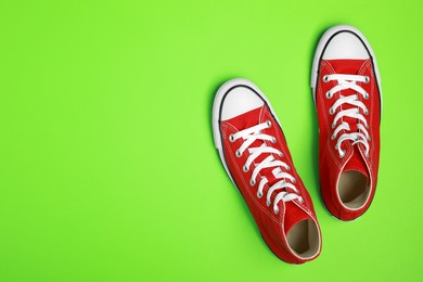 Pair of new stylish red sneakers on light green background, flat lay. Space for text