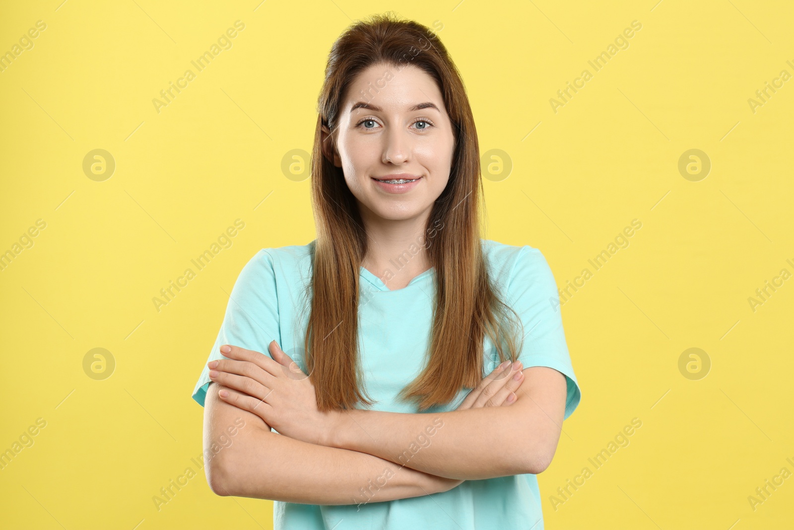 Photo of Portrait of smiling woman with dental braces on yellow background