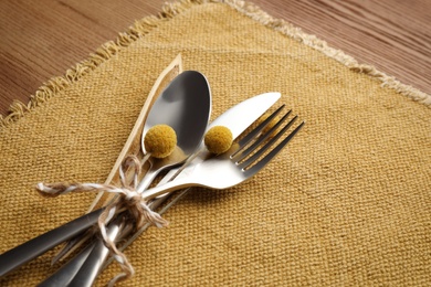 Photo of Set of cutlery, yellow cloth and autumnal decor on wooden background. Table setting elements