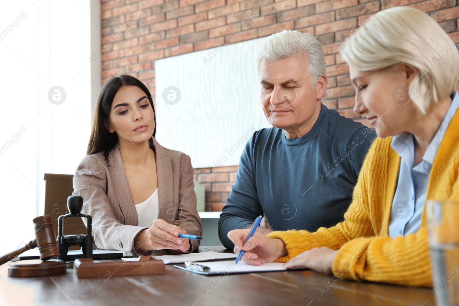 Photo of Female notary working with mature couple in office