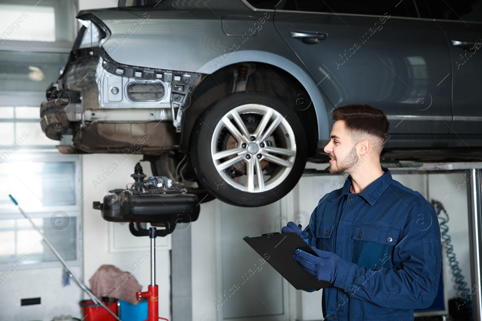 Photo of Technician checking car on hydraulic lift at automobile repair shop