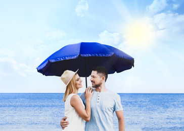 Image of Happy romantic couple with umbrella for sun protection near sea