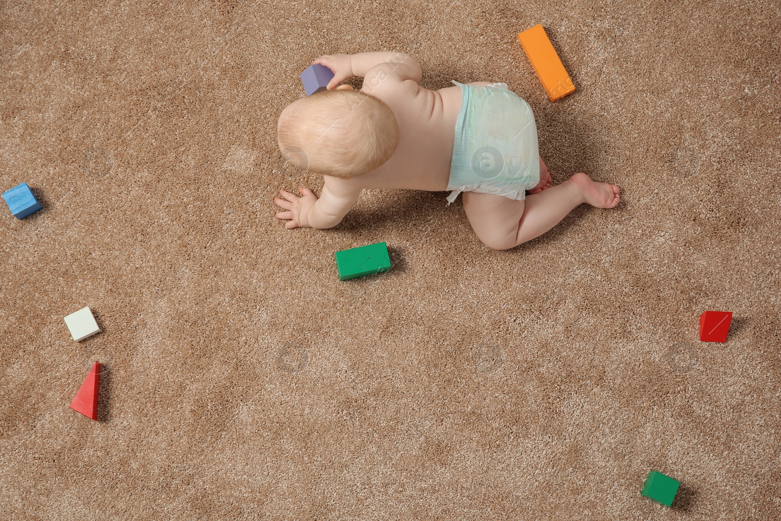 Photo of Cute little baby crawling on carpet with toys, top view. Space for text