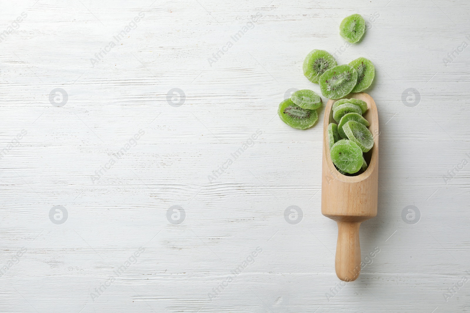 Photo of Scoop of dried kiwi on wooden background, top view with space for text. Tasty and healthy fruit