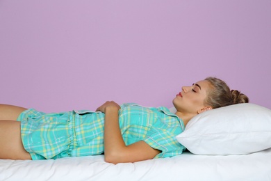 Photo of Beautiful woman sleeping with comfortable pillow on bed against color background