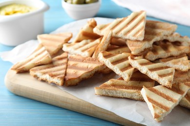 Photo of Delicious pita chips on light blue wooden table, closeup