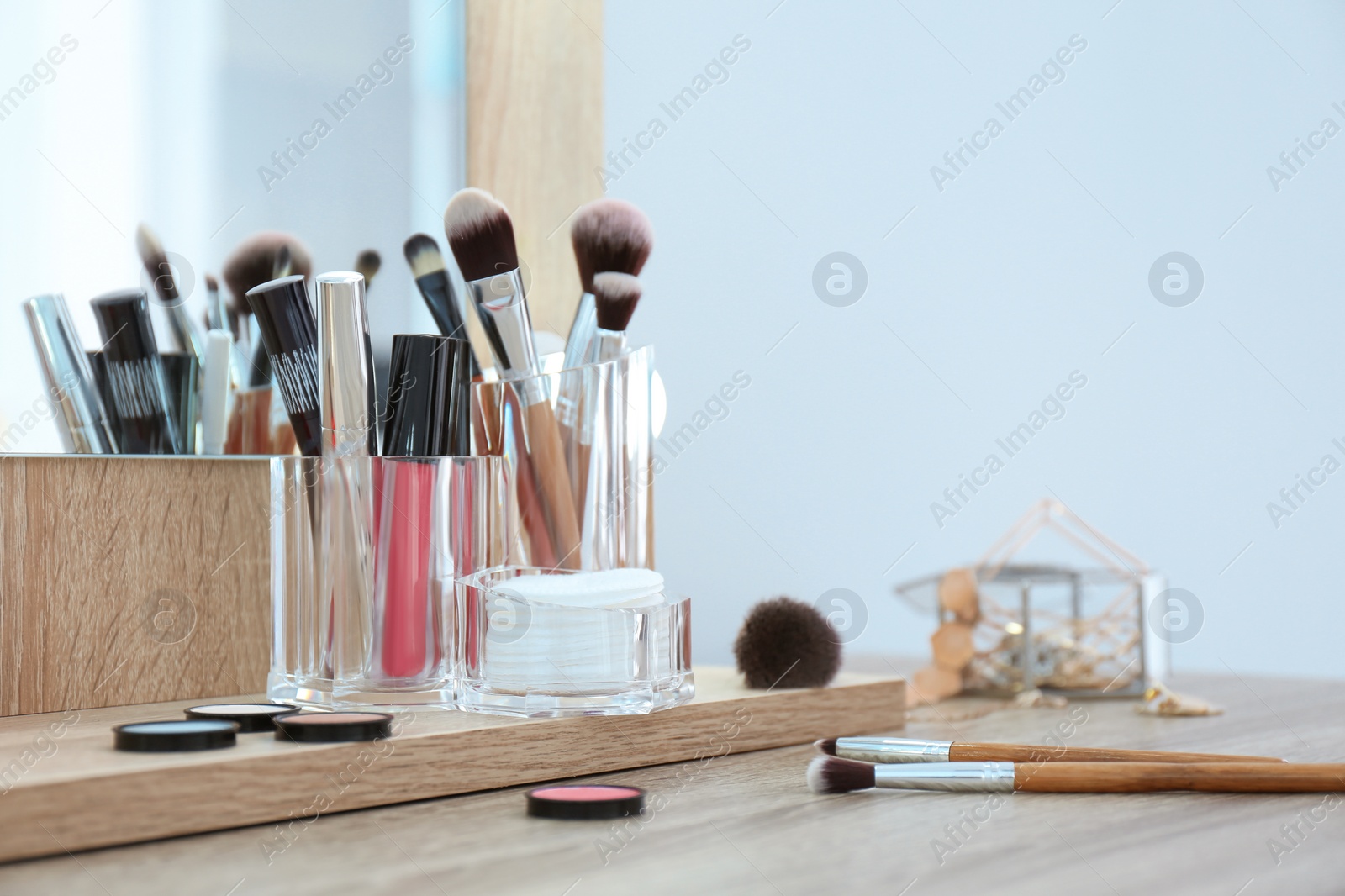 Photo of Organizer with cosmetic products for makeup on table near mirror. Space for text