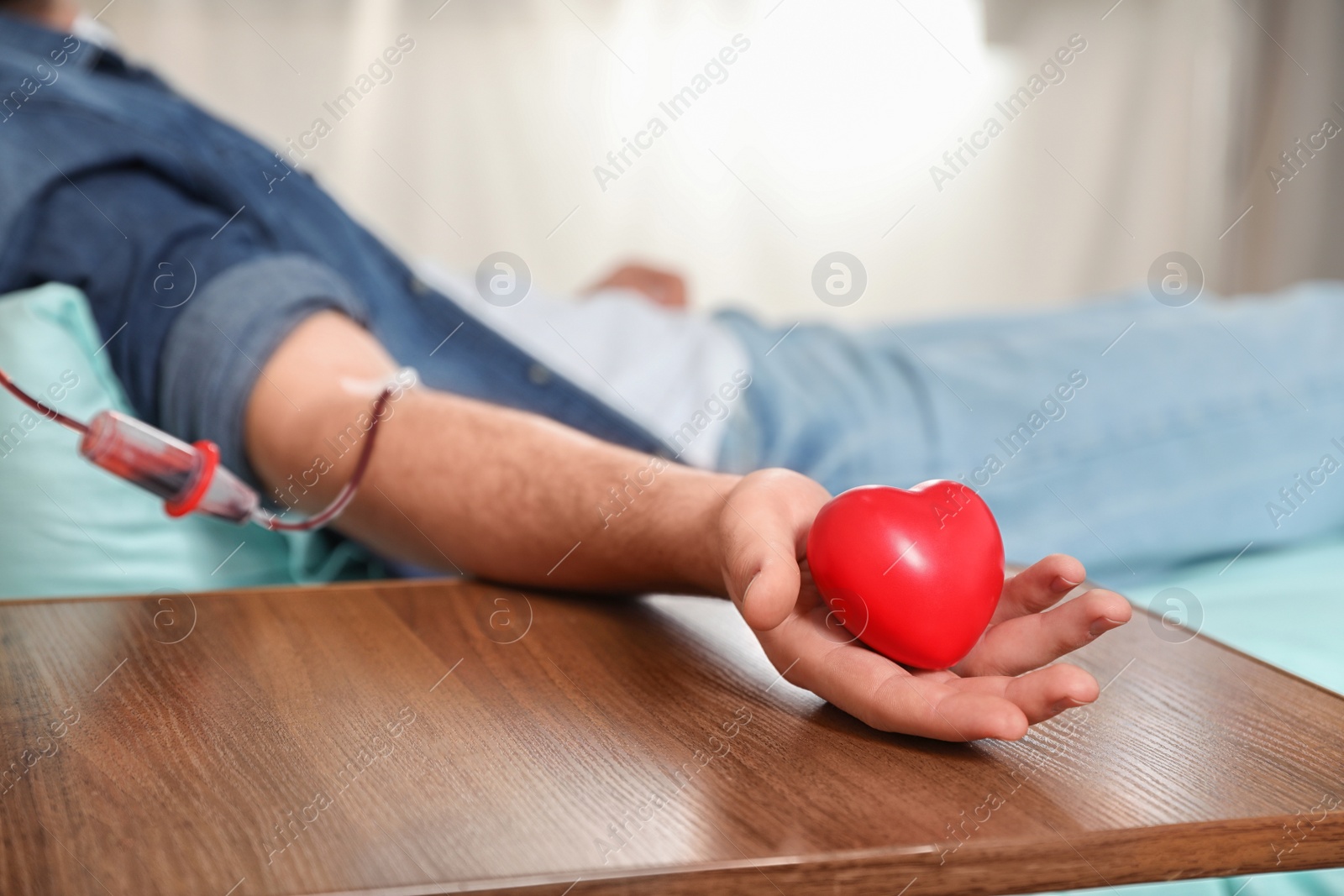 Photo of Young man making blood donation in hospital, closeup