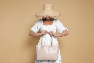 Photo of Young woman with stylish bag on beige background