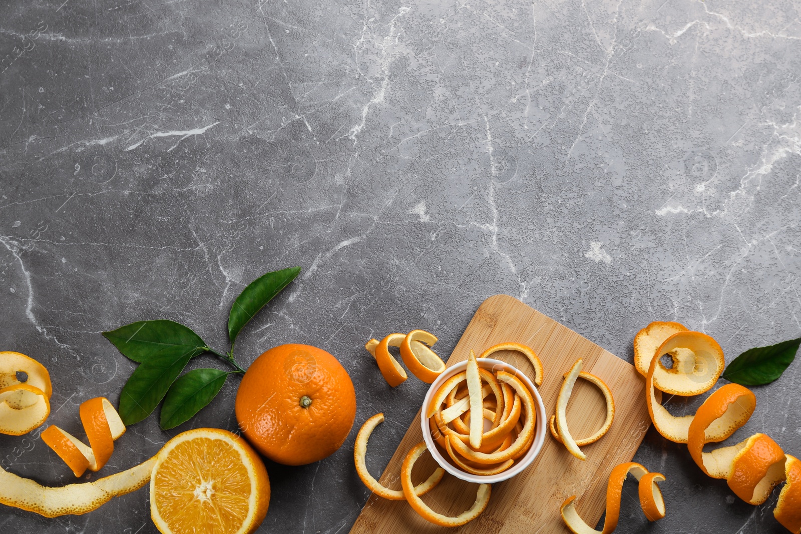 Photo of Orange fruits with peels on grey marble table, flat lay. Space for text