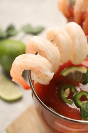 Photo of Tasty shrimp cocktail with sauce in glass on light table, closeup