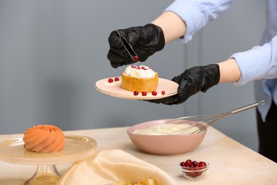 Photo of Food stylist creating composition with delicious dessert on table in photo studio, closeup