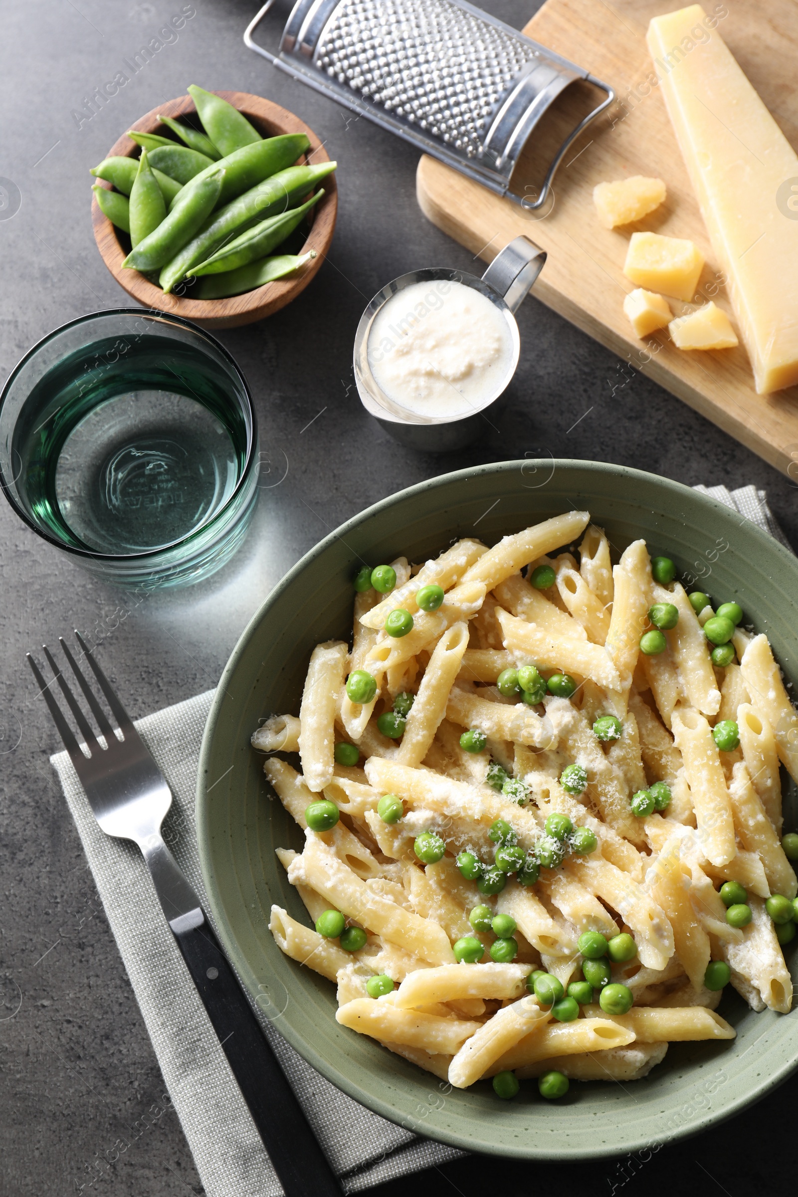 Photo of Delicious pasta with green peas served on grey table, top view