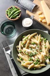 Delicious pasta with green peas served on grey table, top view